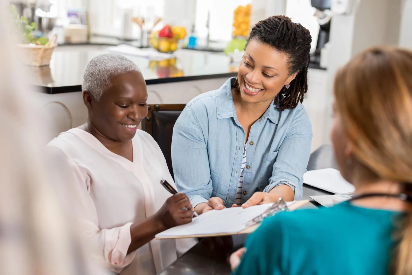 An older woman and her daughter reviewing health care planning documents with a nurse